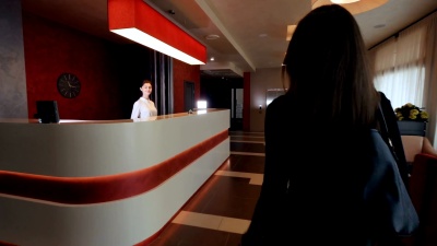 迷人的女人在酒店接待室检查。带着行李去度假。