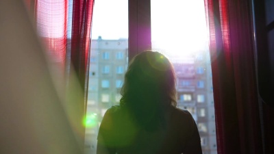 幸福的年轻情侣来到窗前。男孩轻轻地拥抱女孩并亲吻她。太阳光穿过窗户，照亮了房间。