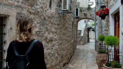 带着兴趣旅行的女人看着狭窄的街道