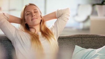 美丽的年轻女子闭着眼睛在家里的沙发上享受自我时刻