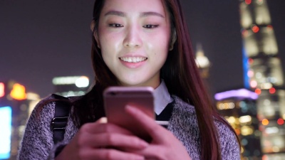 年轻的亚洲女性在现代城市玩手机