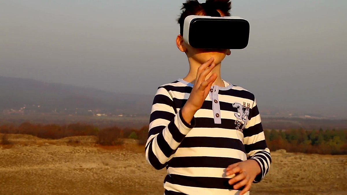 一个小男孩在自然界外面使用虚拟现实眼镜