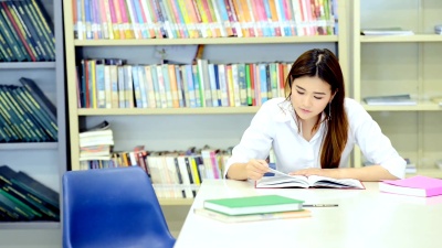 让我们一起完成我们的小组工作。年轻学生一起在图书馆做研究。中国男孩和女孩。