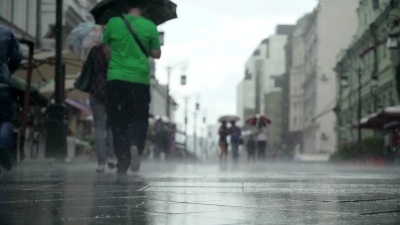 城市街道大雨天的背景。实时。人们在雨中打着伞上下班。拿着五颜六色雨伞的小女孩。模糊的波克。自然背景