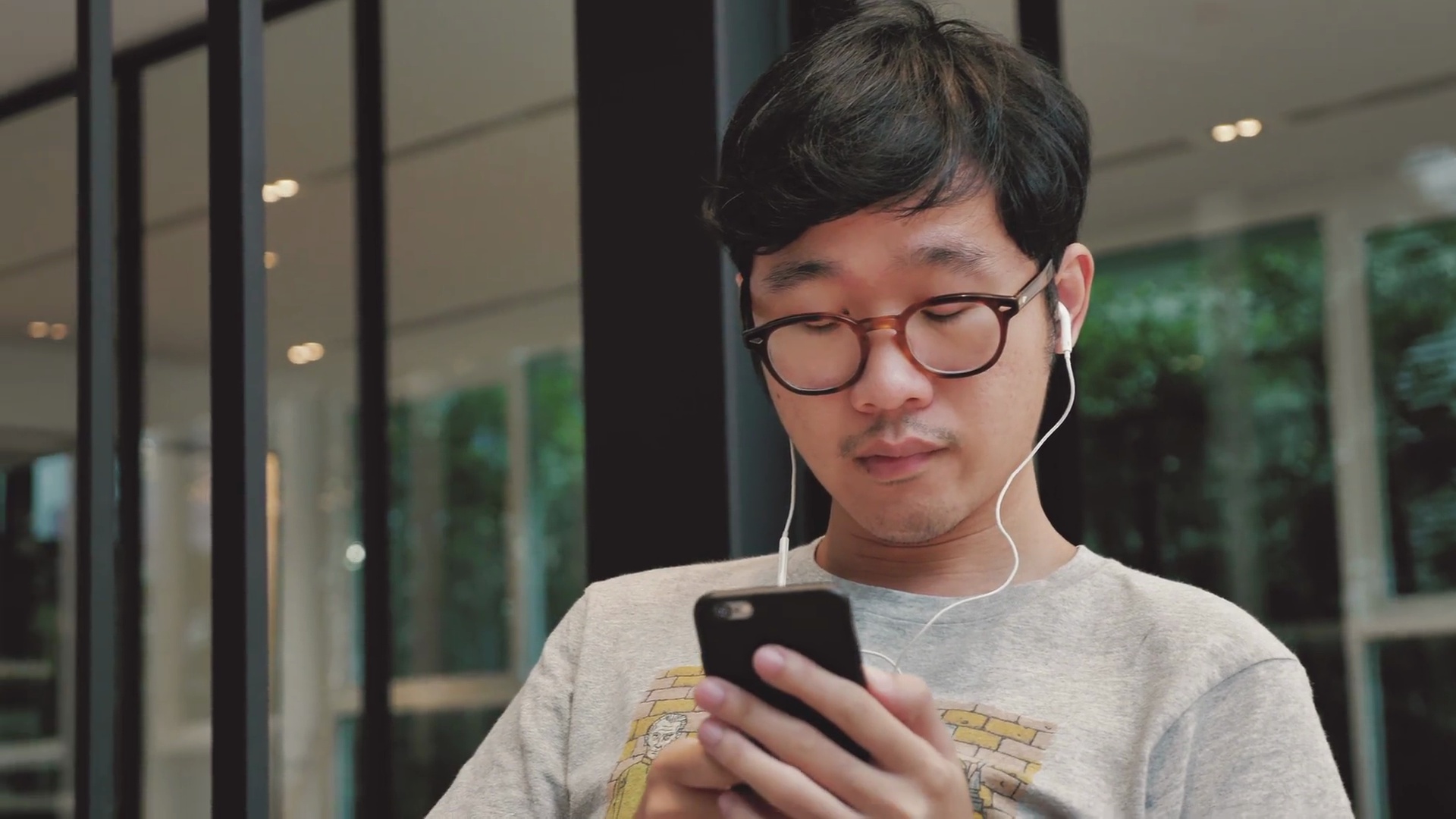 亚洲男人在智能手机上选择和听音乐， 