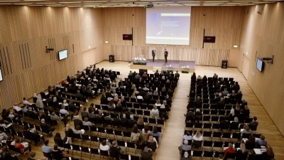 劳工处大型会议厅，讲台上有座位式研讨会与会者和两名演讲者