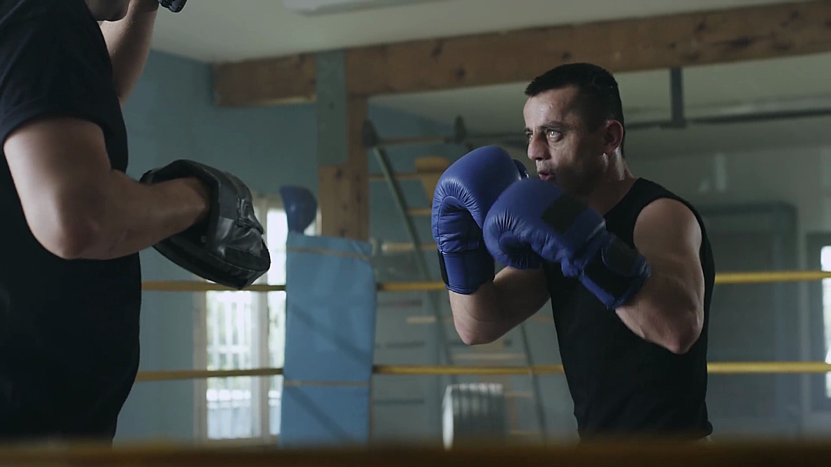 男子拳击手在健身房和教练一起练习