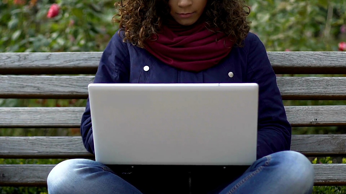 在公园的笔记本电脑上工作的混血儿女性自由职业者，电子商务