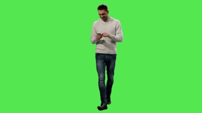 随意的高加索男子在背景中的模拟绿色屏幕上行走和使用智能手机。