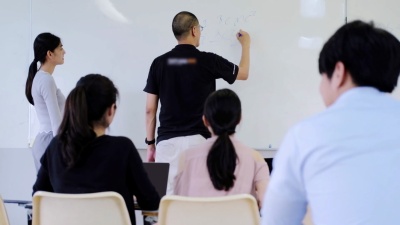 十几岁的学生在课堂上向老师学习，坐在白板上听老师讲课。