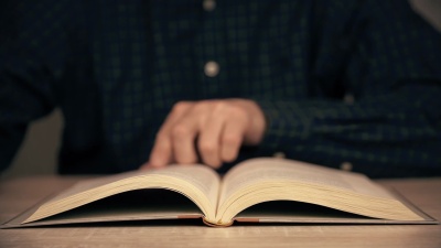 男性在近距离阅读时用手翻动书页。人阅读的书