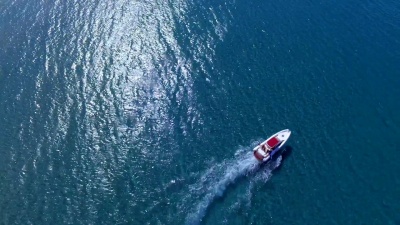 在阳光明媚的日子里沿着海洋或海岸绕圈的摩托艇。