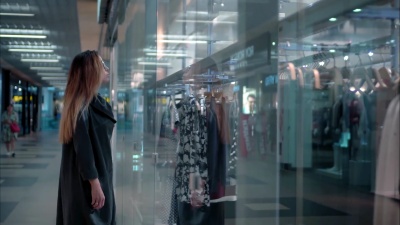 年轻时髦的女人在商店橱窗附近挑选衣服