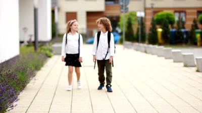 男孩和女孩放学回来聊天。孩子们穿着校服，背着背包