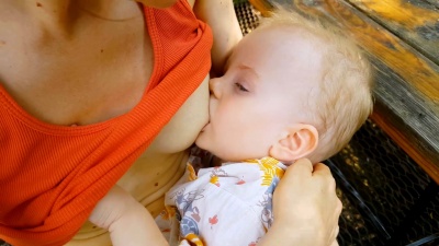 妈妈坐在公园的长椅上哺乳她的宝宝