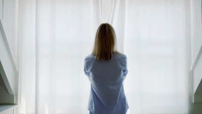 女人打开窗帘向窗外看的后视图