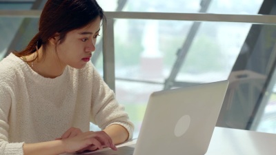 漂亮年轻的亚洲女性在室内电脑上工作， 