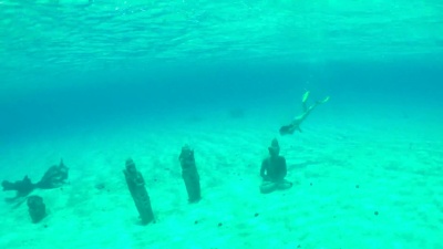水下 年轻女子在热带岛屿泻湖的海底沉没佛像避难所游泳，度过她阳光灿烂的暑假。