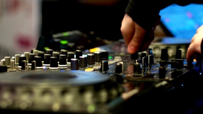 在夜总会工作的DJ音乐家手动操作DJ控制器，远程音频控制调音器在夜总会播放唱片