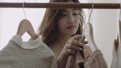 试着从衣架上穿衣服的女人在房间里挂着衣架