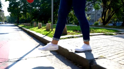 一名女性穿过街道的腿的视频片段。匿名录像。