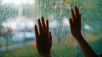 女人用手触摸雨滴的窗户