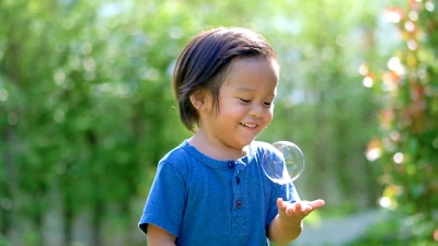 婴儿在户外玩肥皂泡。