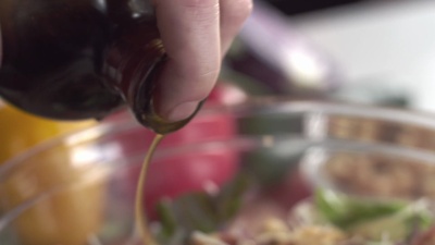 厨师用油和醋调味新鲜花园沙拉的特写镜头