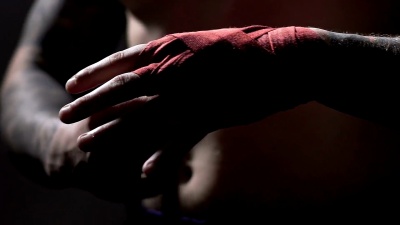 强壮的男性拳击手在打架前用绷带包扎双手，慢动作