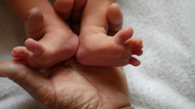 婴儿的脚在母亲的手中。新生婴儿的脚踩在女性身上