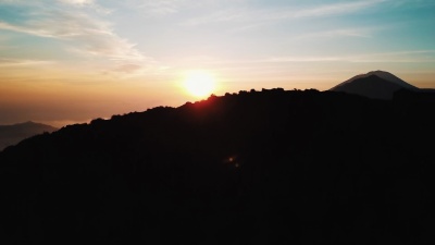 一群朋友跑上山，站在巴厘岛活跃火山巴图尔峰的云顶上，日出航拍 