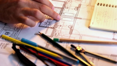 建筑师拿着铅笔工作与笔记本电脑和蓝图的建筑计划，工程师素描一个建设项目的概念。
