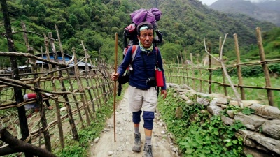 亚洲旅行者带着徒步旅行背包和棍子爬山
