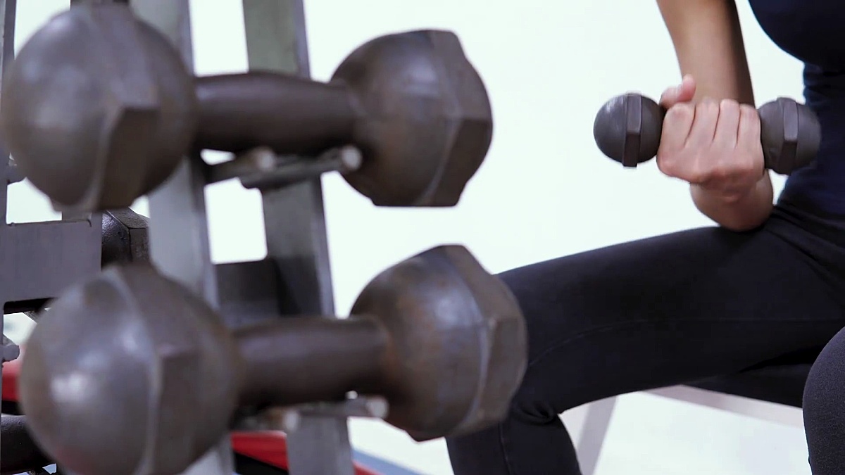 健美女性用哑铃锻炼肌肉和在运动健身房做运动