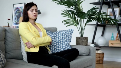 头痛的随意女人坐在家里的沙发上