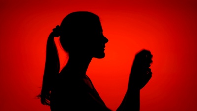 女性涂抹眼药水的剪影。女性的脸部侧面在红色背景上滴下眼珠