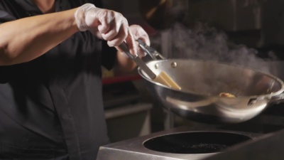 厨师在炒锅里煮肉蔬菜面条的特写镜头