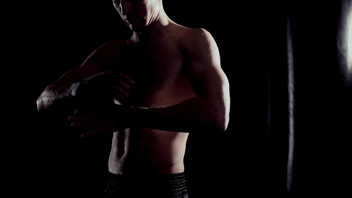 男性拳击手用手巾包住双手。职业拳击手在手上包绷带。拳击手在健身房用拳击套装包裹双手