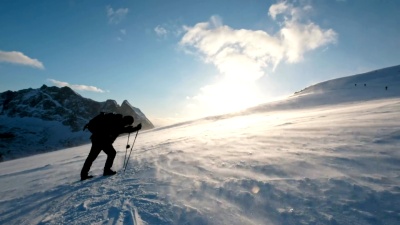 日落时分，人类背包客在山里的风暴中跋涉