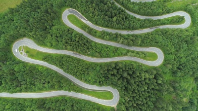 空中自行车手在风景优美的公路上骑自行车下山，并有急转弯