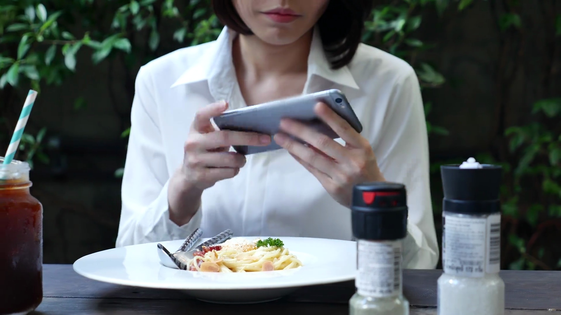 在餐馆拍摄意大利面条食物的女人