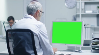 高级医生正在制作一台样机绿屏个人电脑。他的助手在后台工作。Office有一种现代极简主义的感觉。