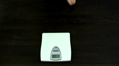 大肚子男人站在量秤上检查体重，饮食结果