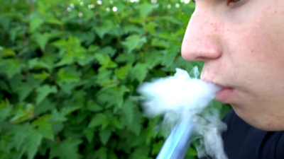 年轻的吸烟者用慢动作的电子烟蒸气呼出大片的烟雾