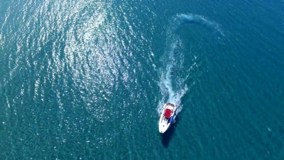 在阳光明媚的日子里沿着海洋或海岸绕圈的摩托艇。
