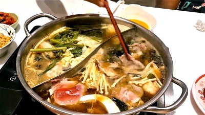 用筷子配猪肉片在日式火锅中煮沸沙布黑豆汤