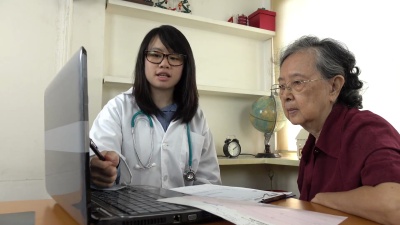 医生用笔记本电脑向老妇人讲解用药