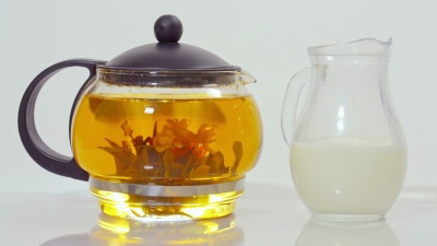 玻璃茶壶里的绿茶和一小壶牛奶