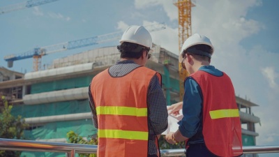 工程师和工头带着蓝图在建筑工地上交谈，推拉镜头