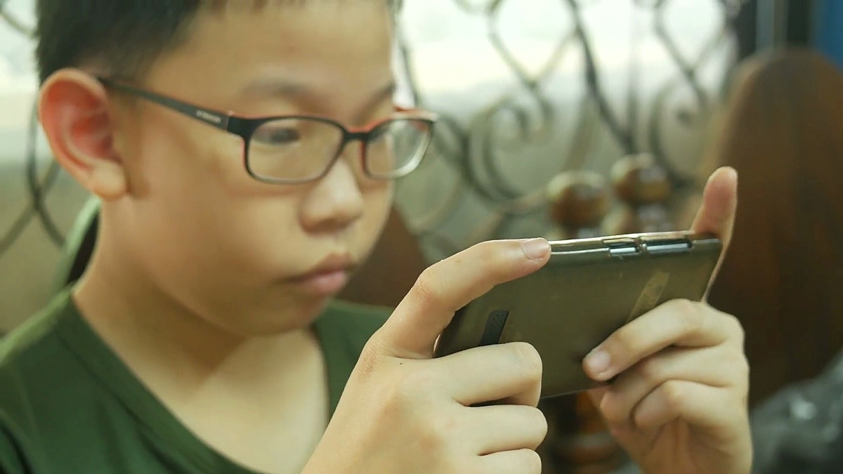 用智能手机玩数码游戏的亚洲男孩